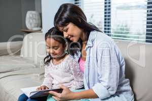 Happy young mother reading a book with her daughter