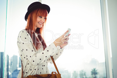 Smiling hipster woman texting with her smartphone