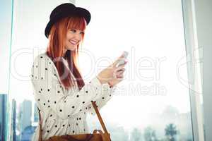 Smiling hipster woman texting with her smartphone