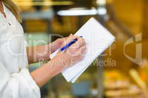 Woman checking list at supermarket