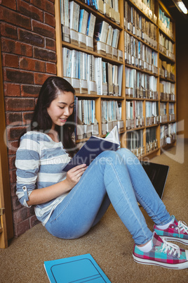 Smiling student sitting on the floor against wall in library rea