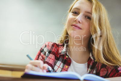 Smiling student writing on notebok