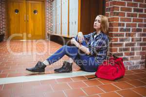 Worried student sitting on the floor against the wall