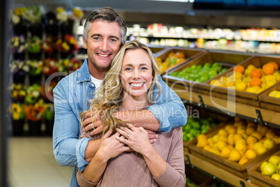 Smiling couple hugging in fruit aisle