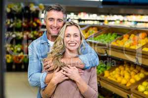 Smiling couple hugging in fruit aisle