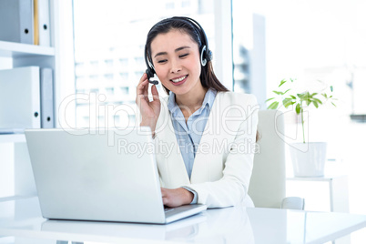 Smiling businesswoman with headset using laptop