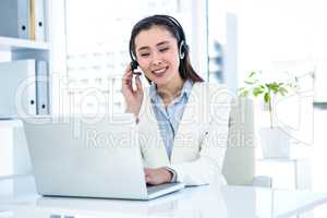 Smiling businesswoman with headset using laptop