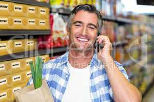 Smiling man on a phone call with grocery bag