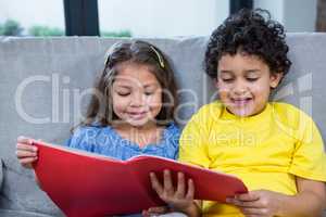 Cute siblings reading a book on the sofa