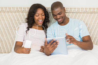 Relaxed couple using technology on bed