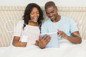 Relaxed couple using technology on bed