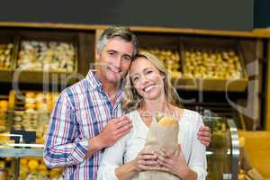 Smiling couple holding bread in paper bag