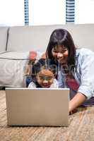 Happy young mother using laptop with her daughter