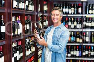 Smiling man holding bottle of wine