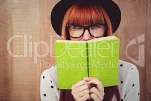 Hipster woman behind a green book