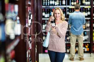Smiling woman holding bottle of wine