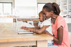 Cute daughter using laptop at desk with mother