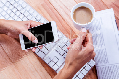 Businesswoman holding hot beverage and smartphone