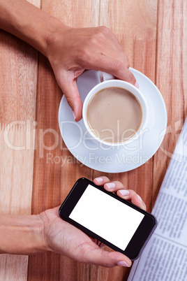 Part of hands holding smartphone and coffee