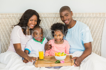 Happy family having breakfast in bed together