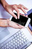 Businesswoman using her smartphone on desk