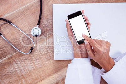 Doctor using smartphone on wooden desk