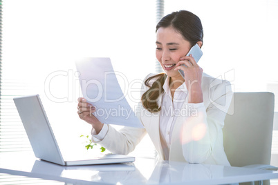 Smiling businesswoman on phone reading document