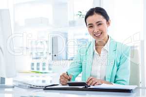 Smiling businesswoman with notes at desk