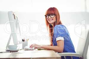 Smiling hipster woman typing on keyboard