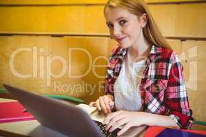 Smiling student using laptop during class