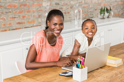 Cute daughter using laptop at desk with mother