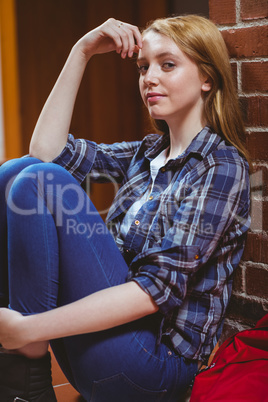 Thoughtful student sitting on the floor against the wall and loo