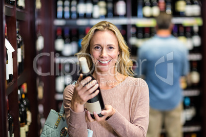 Smiling woman holding bottle of wine