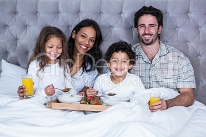 Happy family having breakfast on bed