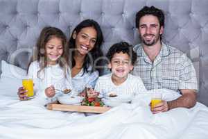 Happy family having breakfast on bed