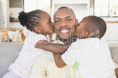 Happy father is kissed by his two children