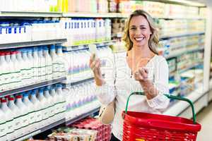 Smiling woman holding smartphone and shopping basket