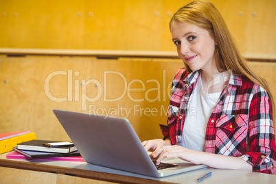 Smiling student using laptop during class