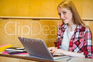 Smiling student using laptop during class