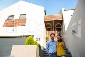 Happy couple in front of new house showing keys
