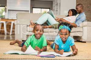 Happy siblings on the floor drawing