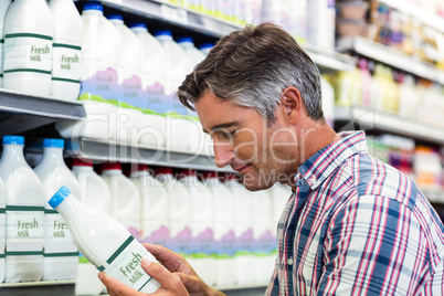 Handsome man in the supermarket looking at milk bottle