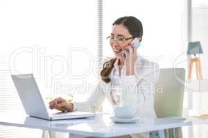 Smiling businesswoman on phone using laptop