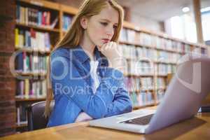 Focused student using laptop in library