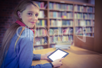 Pretty student with headphones using tablet in library