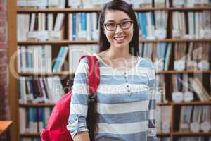 Smiling student with backpack standing in library