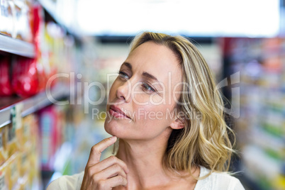 Thoughtful woman looking at shelves