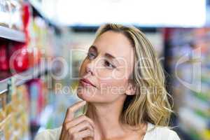 Thoughtful woman looking at shelves