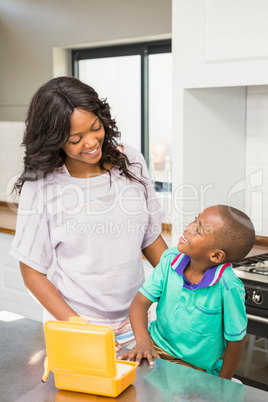 Smiling mother preparing sons school lunch