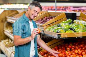 Smiling man choosing a tomato